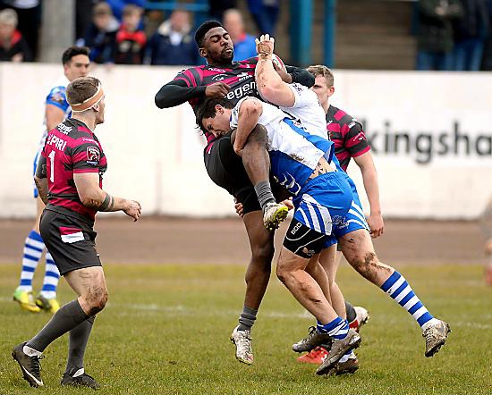 HALTED . . . Oldham’s Jamal Chisholm (centre) is halted by two Workington defenders.