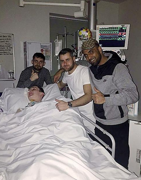 IN good spirits . . . Ellis is flanked by friends and relatives at Salford Royal Hospital