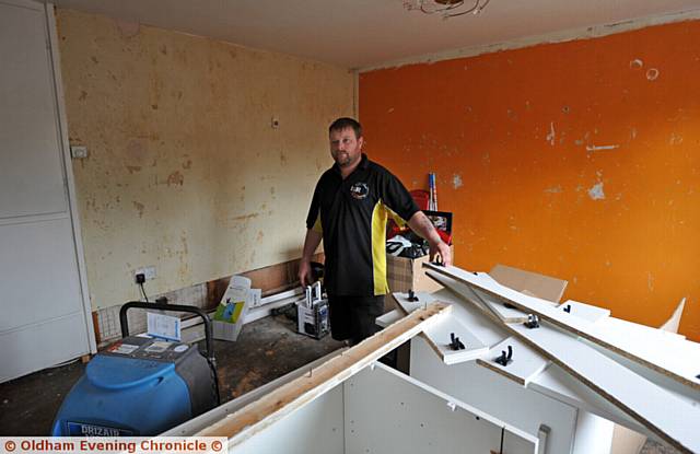 FLOODED out . . . Neil with the kitchen units he has had to move into the living room