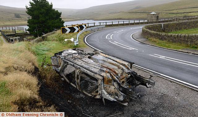 The burnt-out shell of a car left on Huddersfield Road, Denshaw near New Years Bridge Reservoir.
