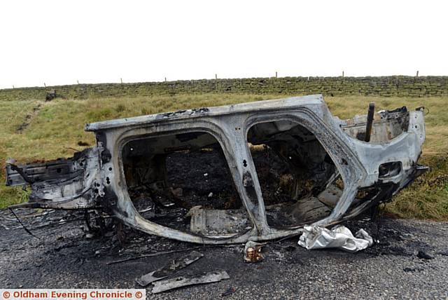 The burnt-out shell of a car left on Huddersfield Road, Denshaw near New Years Bridge Reservoir.