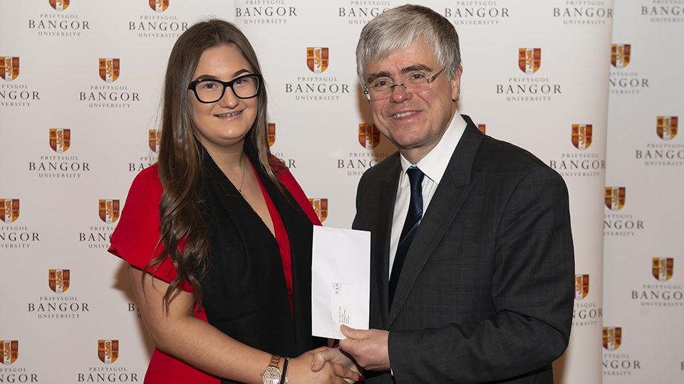 Liberty Kwai Wilcox is pictured receiving an award from Professor Iwan Davies, Vice-Chancellor of Bangor University
