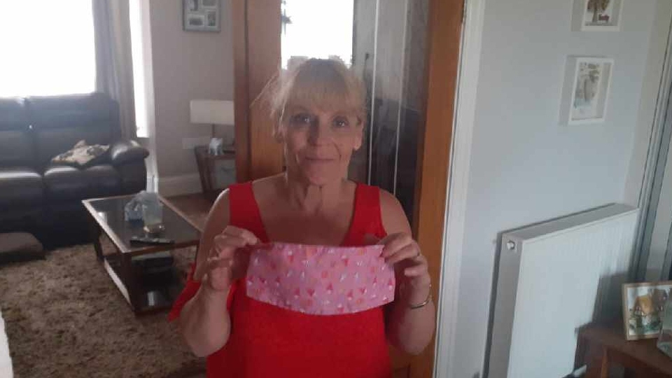 Carole is pictured holding one of the headbands she has made at home