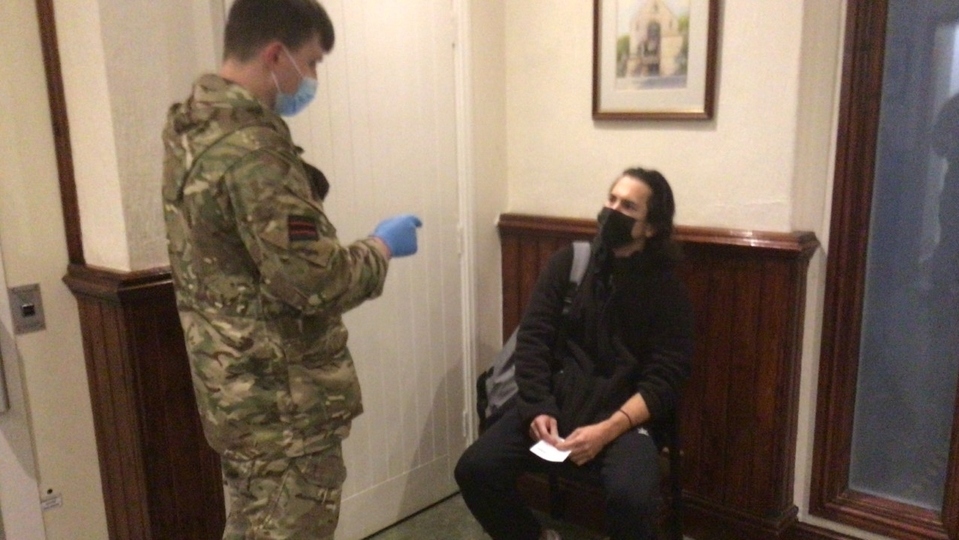 A soldier from the Rifles is pictured talking to a man who turned up to be tested at Uppermill Civic Hall