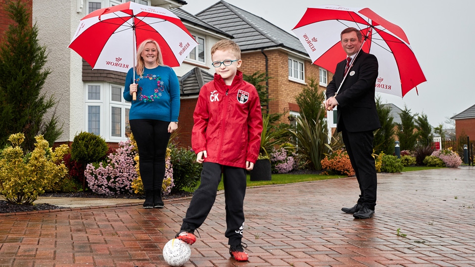 Charlie Kearney from Springhead AFC poses in his new kit funded by Redrow, with mum Felicity Kearney & Redrow's Michael Deegan 