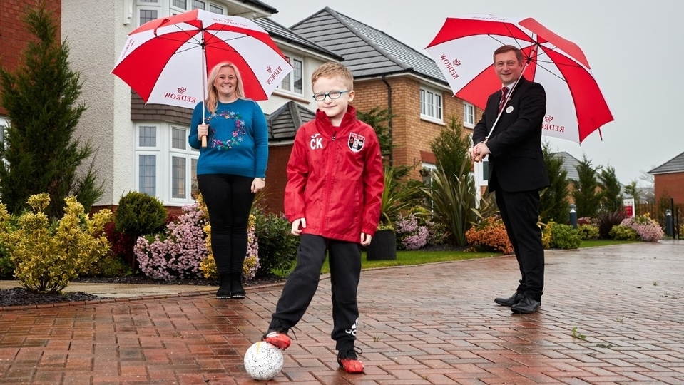 Charlie Kearney from Springhead AFC poses in his new kit funded by Redrow, with mum Felicity Kearney and Redrow sales consultant Michael Deegan at Saddleworth View (photo taken pre-national lockdown) Charlie Kearney from Springhead AFC poses in his new kit funded by Redrow, with mum Felicity Kearney and Redrow sales consultant Michael Deegan at Saddleworth View (photo taken pre-national lockdown)