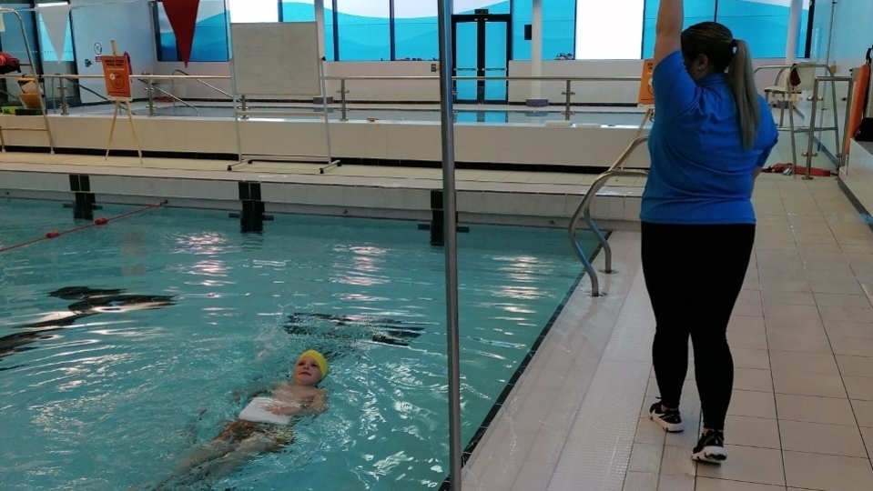 Isaac is pictured in the pool as his swimming teacher, Jordanne Alston, guides him