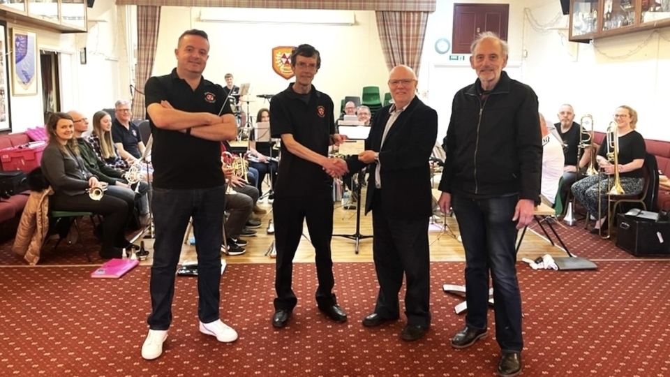 Community Chairman Jon Stocker and President Ian Brett, right, from Saddleworth Rotary, present a cheque to Band Chairman Andy Black and Musical Director Jason Smith