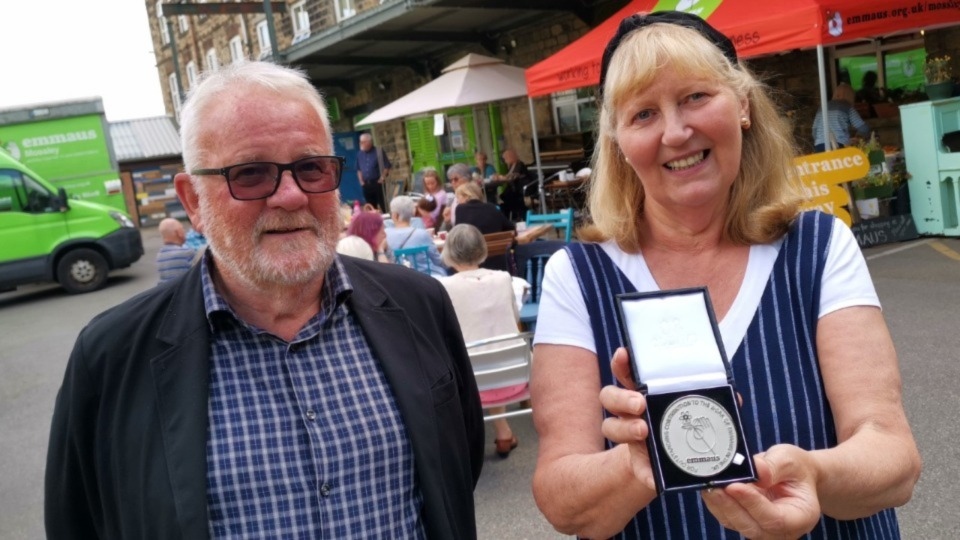 Andrew Kilburn, Chair of Emmaus Mossley, and artist Tonie Rigby with her medal