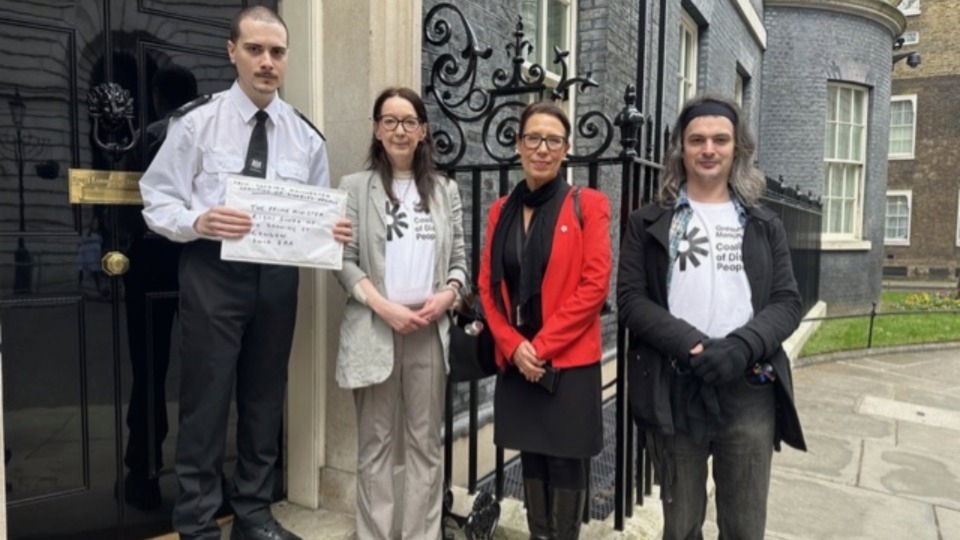 Pictured (left to right): A Downing Street security guard accepts the petition from Helen Rowlands, representing the Greater Manchester Coalition of Disabled People; Debbie Abrahams, MP for Oldham East and Saddleworth; and Pete Marshall, also GMCDP Pictured (left to right): A Downing Street security guard accepts the petition from Helen Rowlands, representing the Greater Manchester Coalition of Disabled People; Debbie Abrahams, MP for Oldham East and Saddleworth; and Pete Marshall, also GMCDP