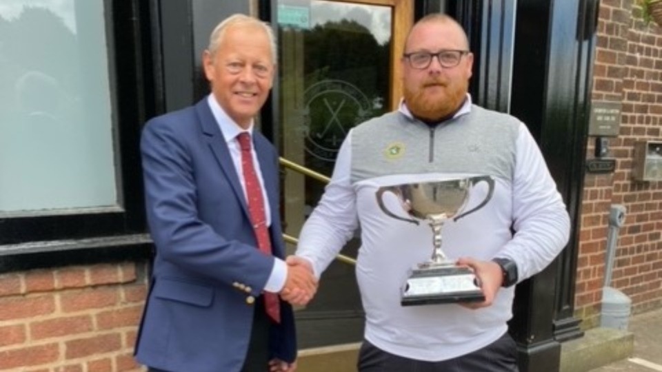 Adam Rowbotham receives the District Championship trophy from Dion Norbury, captain of host club Crompton and Royton