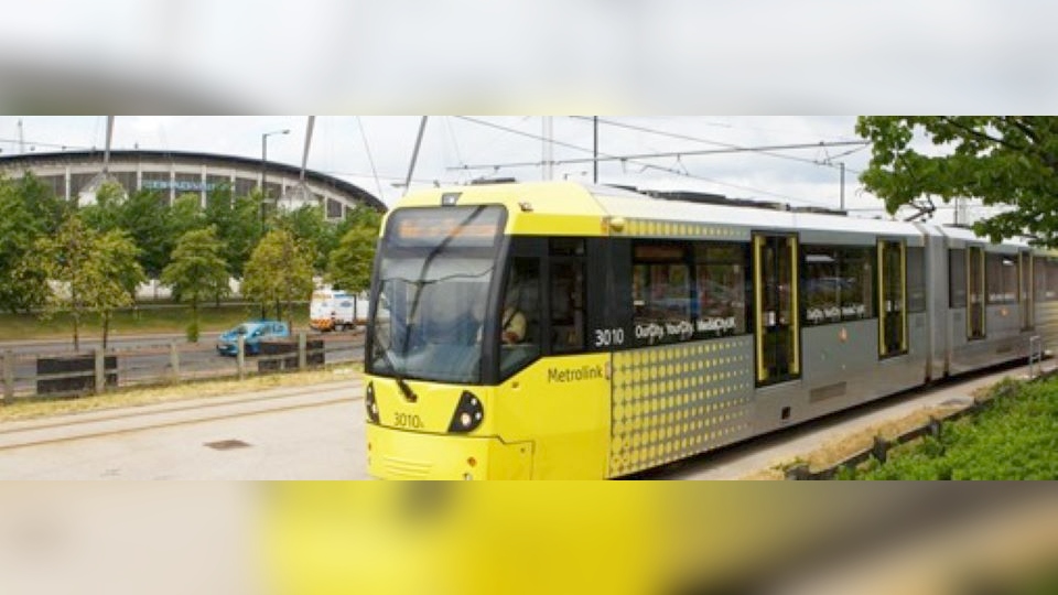 A Metrolink tram goes past the Etihad stadium. Image courtesy of TfGM