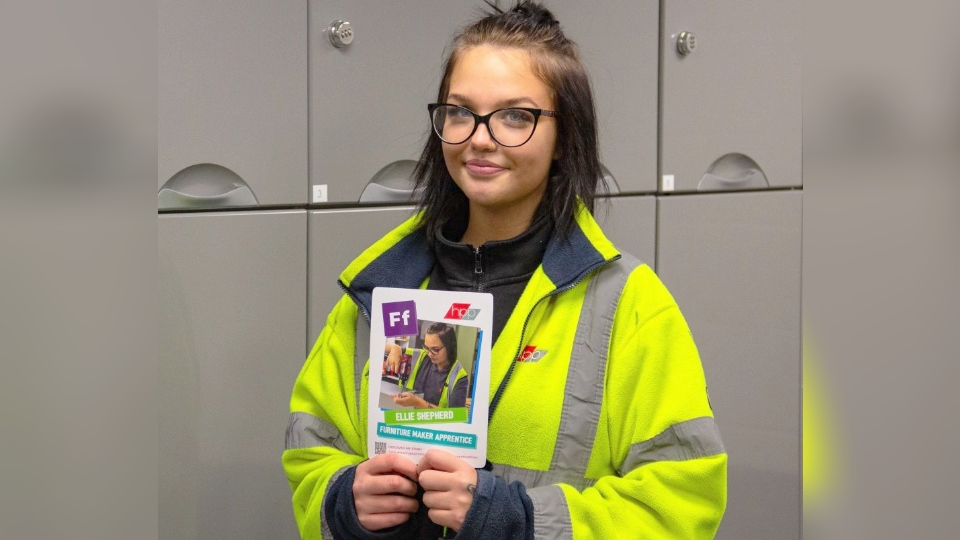 Ellie holding her ‘F for furniture maker’ card from the ‘Apprenticeship A-Z of Women at Work’ pack