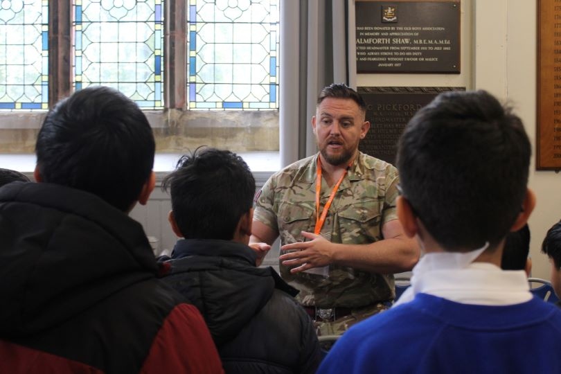 A member of the armed forces talking to students 