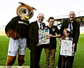 TOP DESIGNS James Bowker and Jessica Smith receive their framed posters from Latics Chief Executive Alan Hardy and Chronicle Editor David Whaley — with Chaddy the Owl looking on. 

