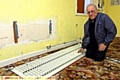 TREASURER Ian Deas surveys the damage to sodden carpets after thieves stole copper pipes from radiators 