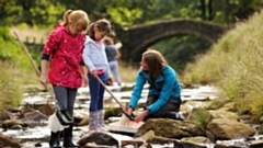Children dipping for wildlife in a stream at Eastergate on the Marsden Moor estate