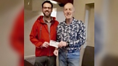 OMRT's Adam Knight receives the £1,800 cheque from Clint Elliott, vice president of Saddleworth Rotary Club