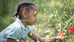 A young girl looking at some beautiful wildflowers